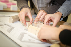 Studierende platzieren Holzbausteine ihres Holzmodells.